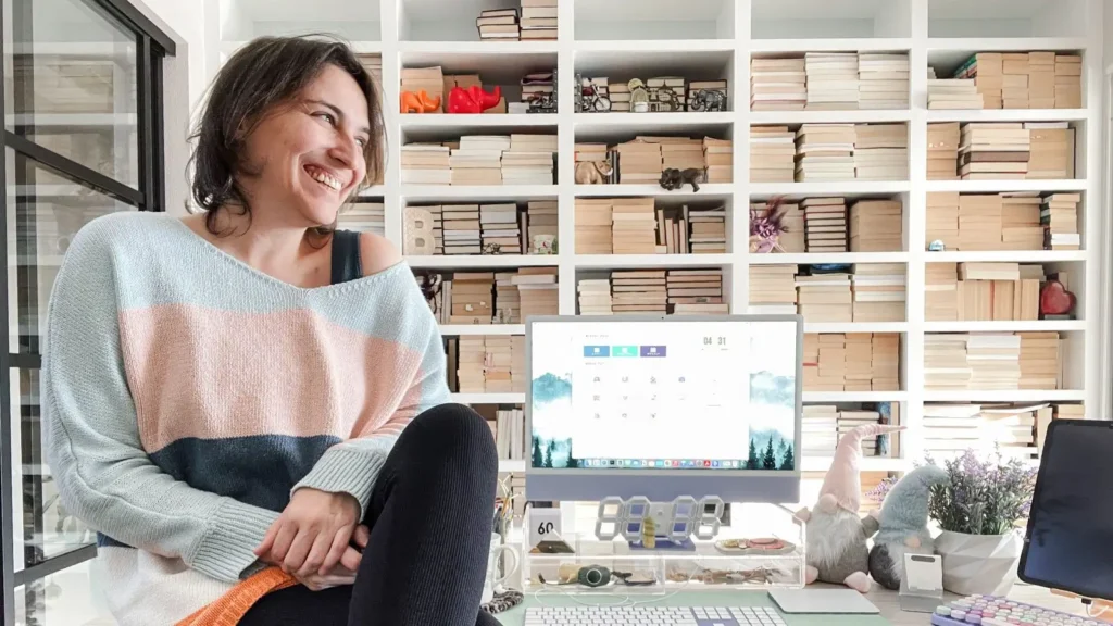 White bookshelves pages turned out on the background and Francesca sitting on a desk in front of them