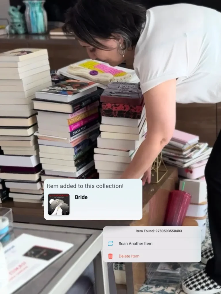 Francesca scanning books with the Libib app while organizing stacks of books for a home library inventory.