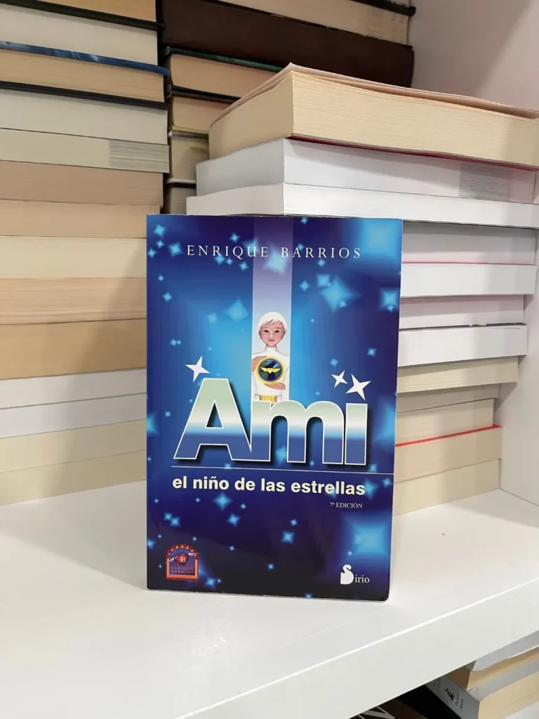 Spanish paperback of Ami: El Niño de las Estrellas by Enrique Barrios on a shelf of stacked books.